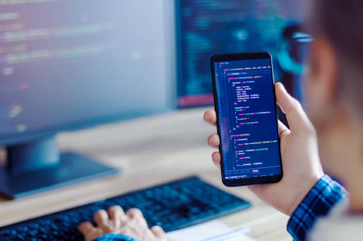 A person holding a smartphone displays code, highlighting the development of different types of mobile apps.